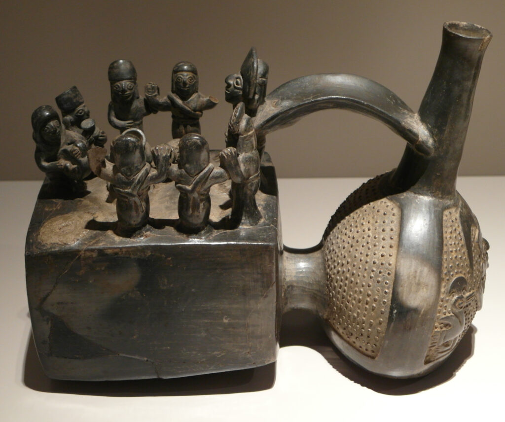 An ancient black whistle showing Andean Indigenous people dancing and drinking chicha.