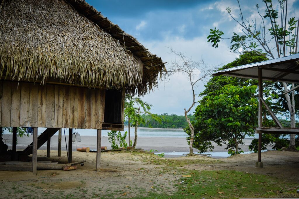 A tatched hut on stilts beside a river in the Ecuadorian Amazon.