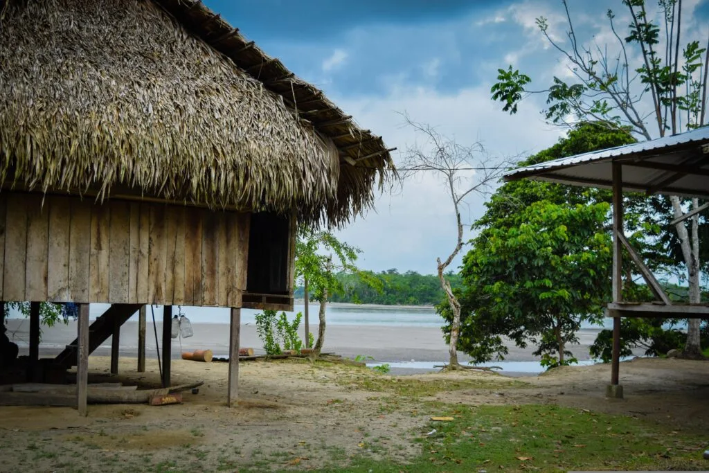 A tatched hut on stilts beside a river in the Ecuadorian Amazon.
