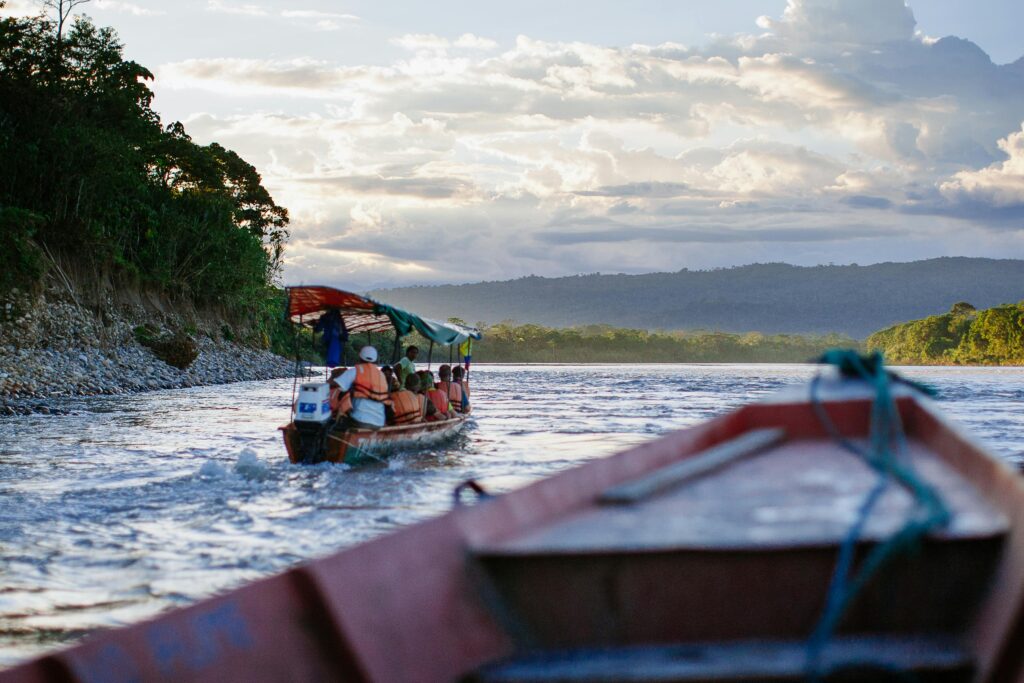 Boats float down the Napo river surrounded by the Amazon Rainforest near Tena, Ecuador.