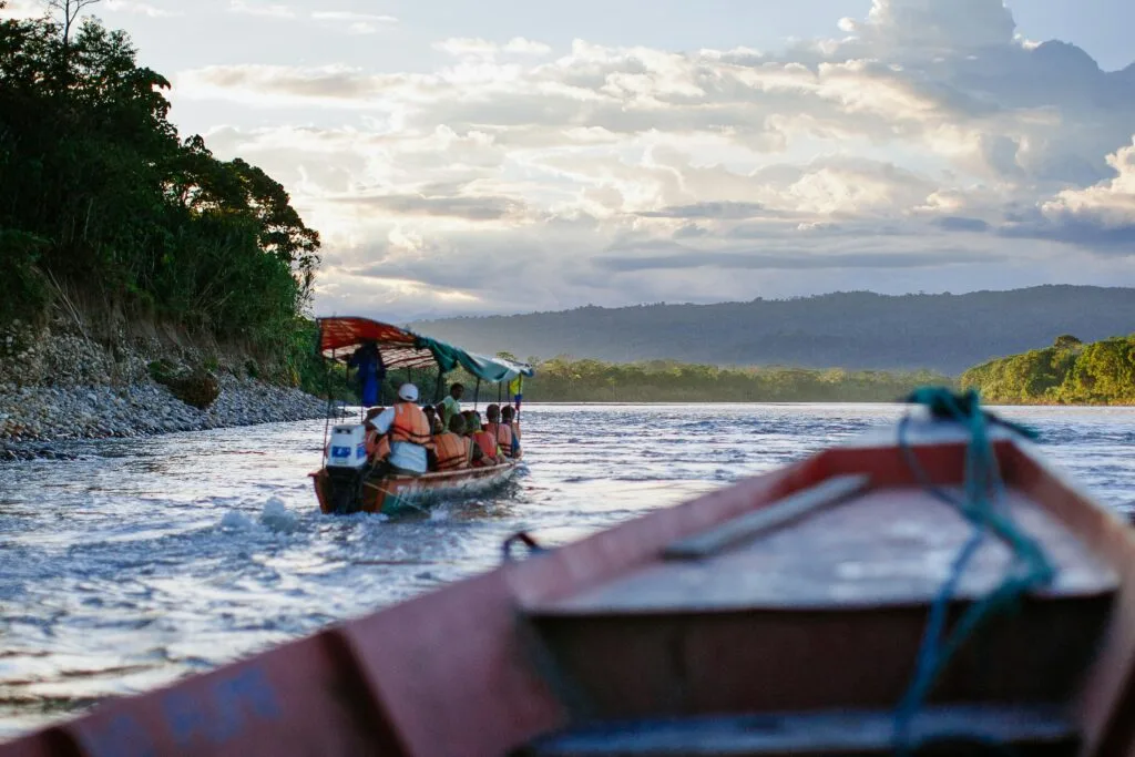 Boats float down the Napo river surrounded by the Amazon Rainforest near Tena, Ecuador.