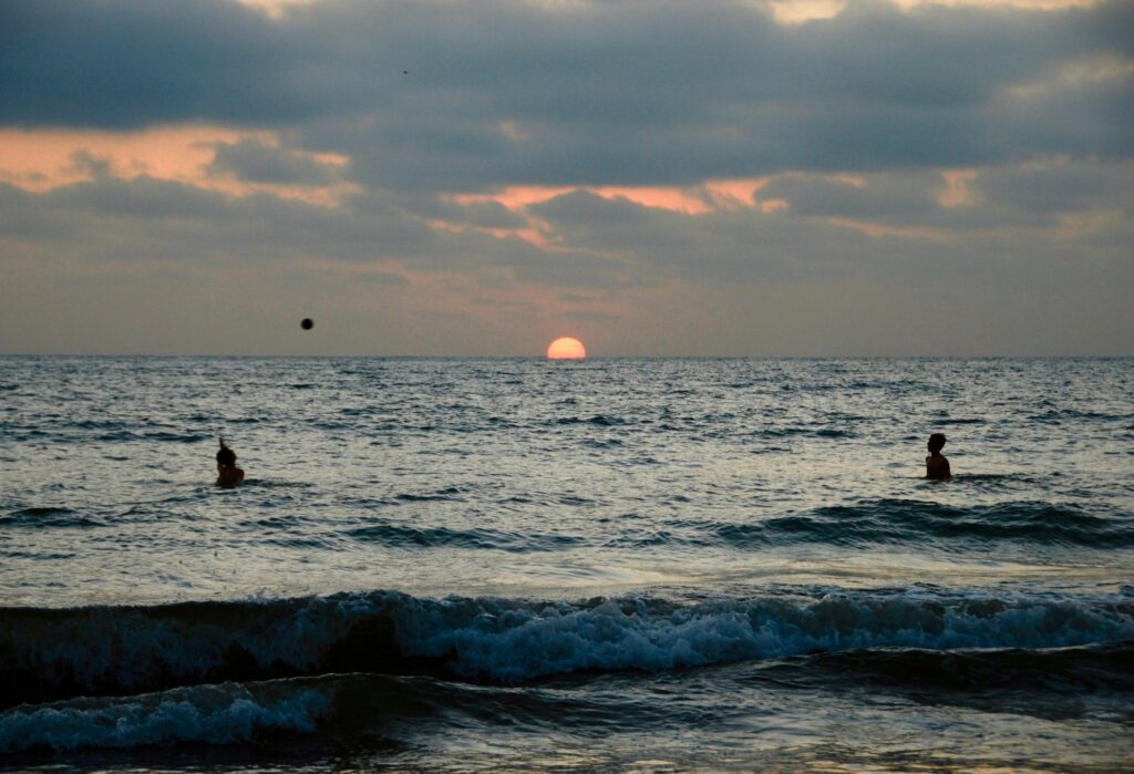 Two people play volleyball in the Pacific Ocena at sunset in Puerto López, Ecuador.
