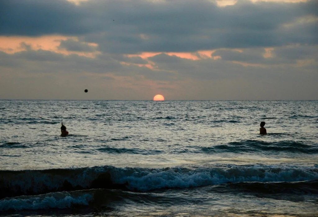 Two people play volleyball in the Pacific Ocena at sunset in Puerto López, Ecuador.