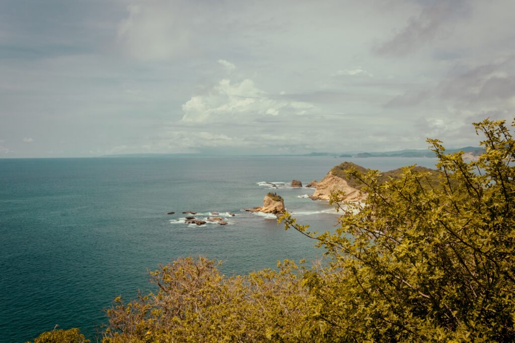 A headland on Los Frailes Beach can be seen with waves breaking against it.
