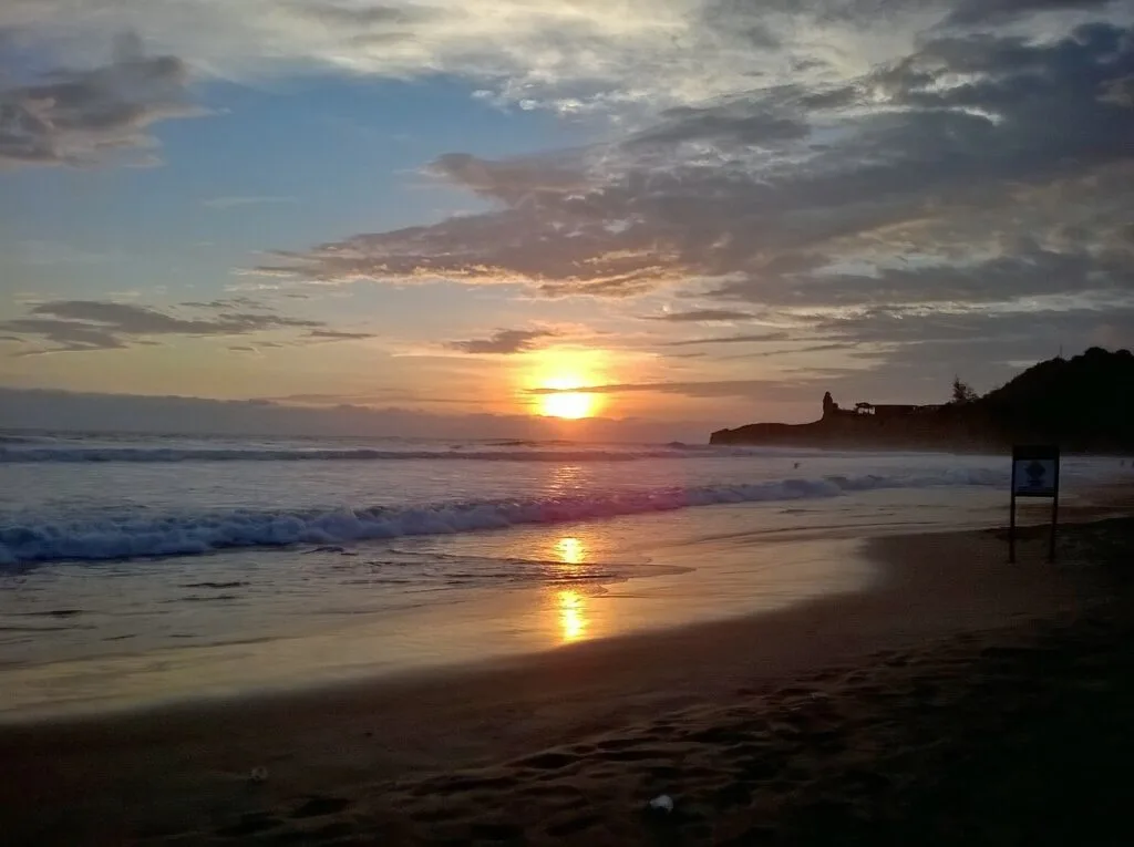 The sun sets over the Pacific Ocean and beach in Montañita, Ecuador.