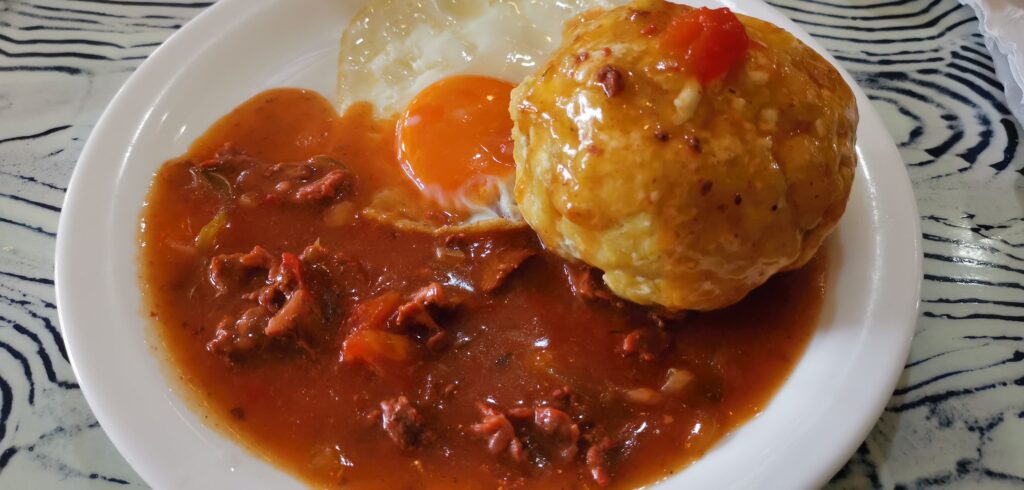 A plate of bolón de verde, fried egg and sauce in Ecuador.
