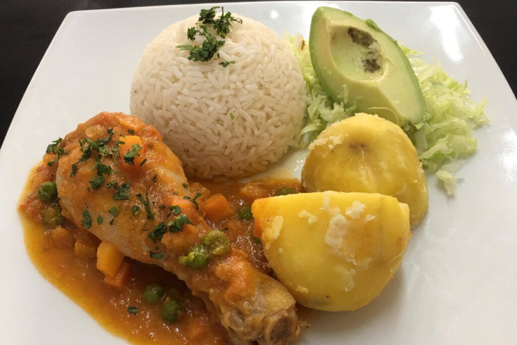 Seco de Pollo — a traditional dish from the Ecuadorian coast, consisting of a Creole tomato sauce made with naranjilla and beer. It is served with rice and potatoes.