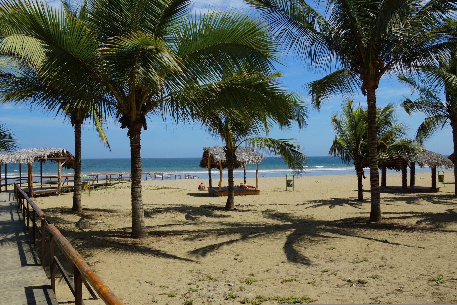 Beach huts under palm trees beside the Pacific Ocean in Puerto Lopez, Ecuador.