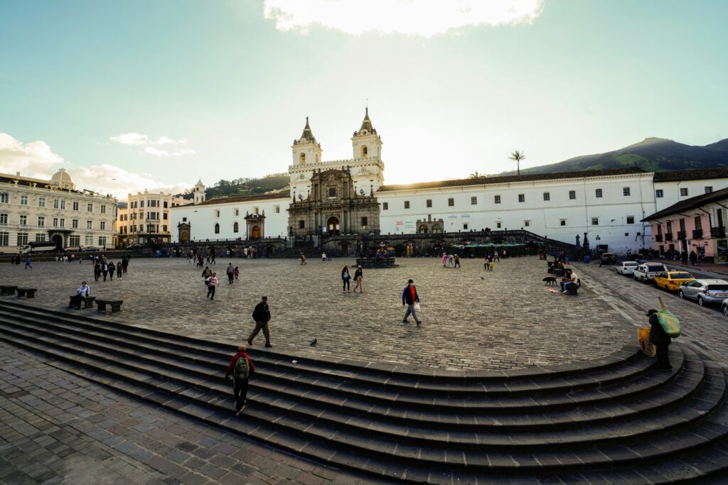 People walk through the Plaza de San Francisco, with the church and convent of the same name in the background
