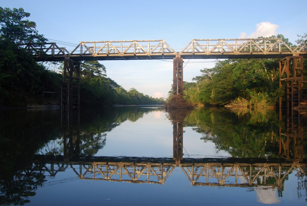A bridge crosses a river in the Amazon, Ecuador. The water is so still it could be a mirror. Wheely Tyred Food in Tena