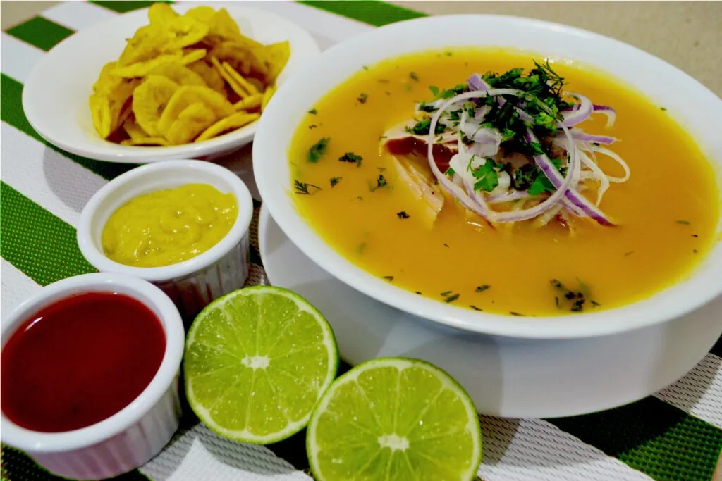 A bowl of encebollado, a fish and onion soup, surrounded by lemon and chilli pepper sauce.