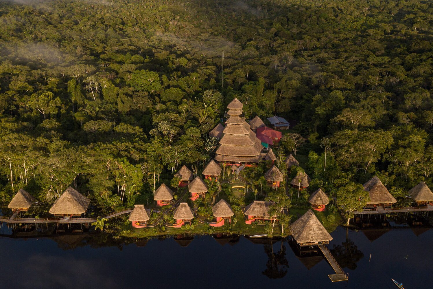 An aerial shot of the Napo Wildlife Center Ecolodge showing the complex of thatched roofs between a lake and the jungle in Yasuní, Ecuador.