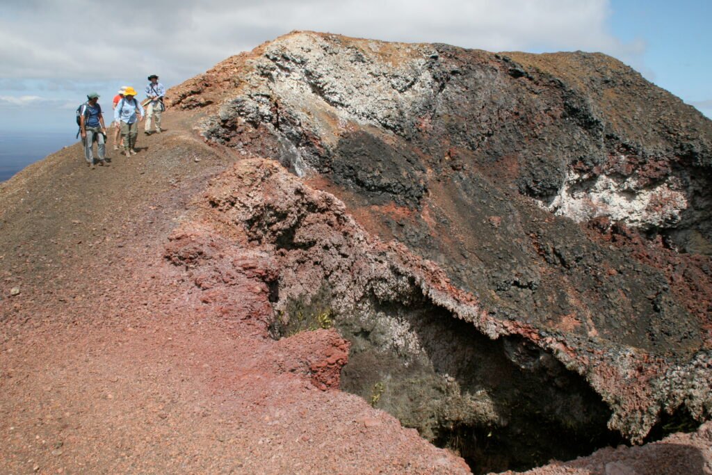 People hike along the calder of the Sierra Negra Volcano on Isla Isabela, Ecuador.