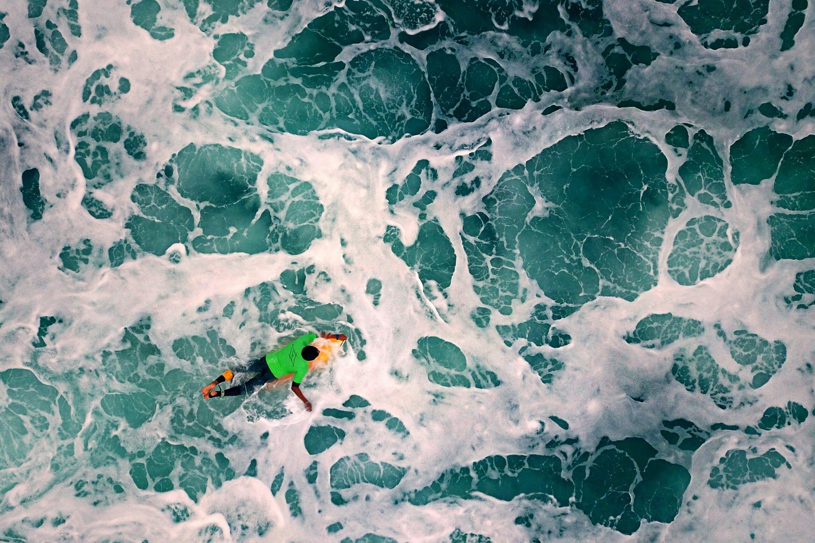 A man paddles his surfboard through the waves in Montanita, Ecuador.
