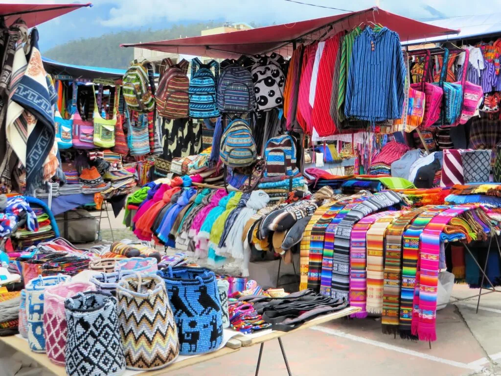 Racks of brightly coloured indigenous garments on sale in a plaza market in Otavalo, Ecuador.