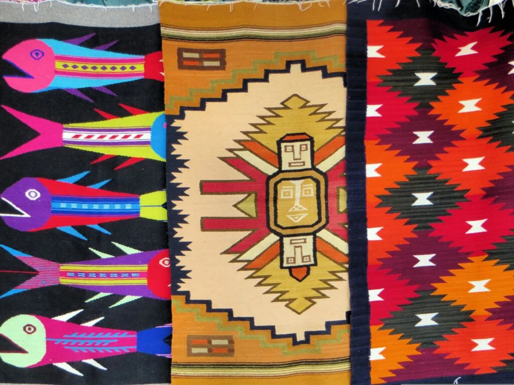Three brightly coloured ponchos on sale in a plaza market in Otavalo, Ecuador.
