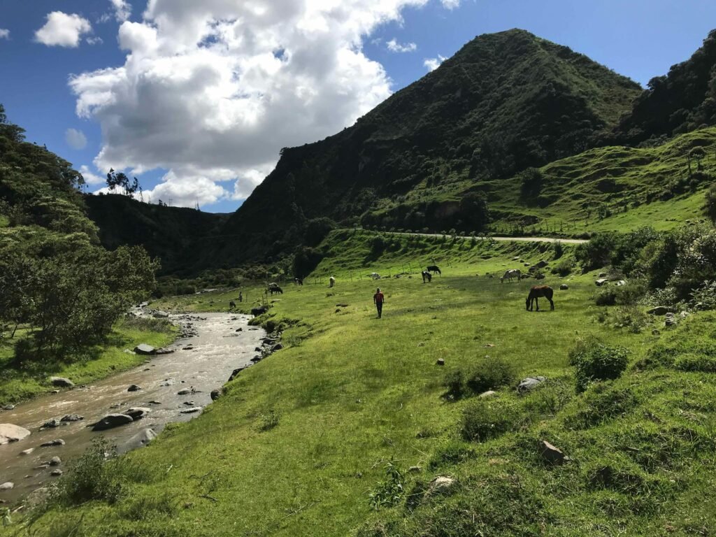 A river flows through green meadows and mountains of the Isinliví, Sigchos, Quilotoa Loop, Ecuador.