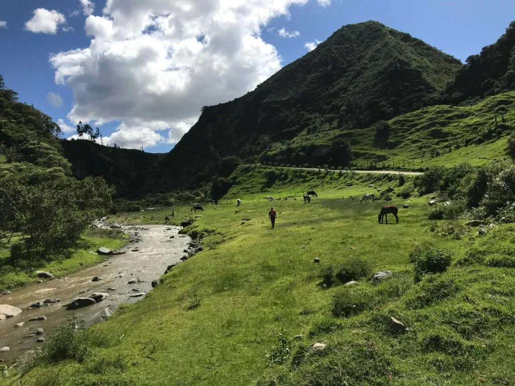 A river flows through green meadows and mountains of the Isinliví, Sigchos, Quilotoa Loop, Ecuador.