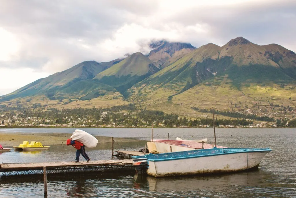A man unloads a small boat under the volcanoes on a Lake in Ecuador. Wheely Tyred Best places to eat in Otavalo