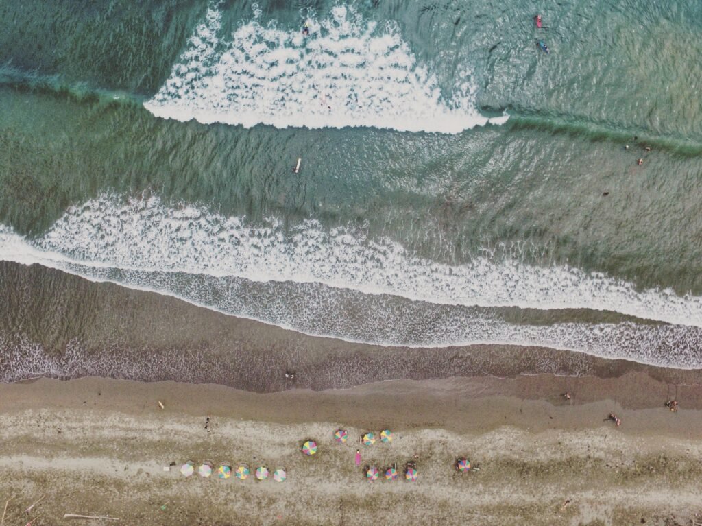 Waves crash against a beach in an aerial shot. Wheely Tyred Puerto López