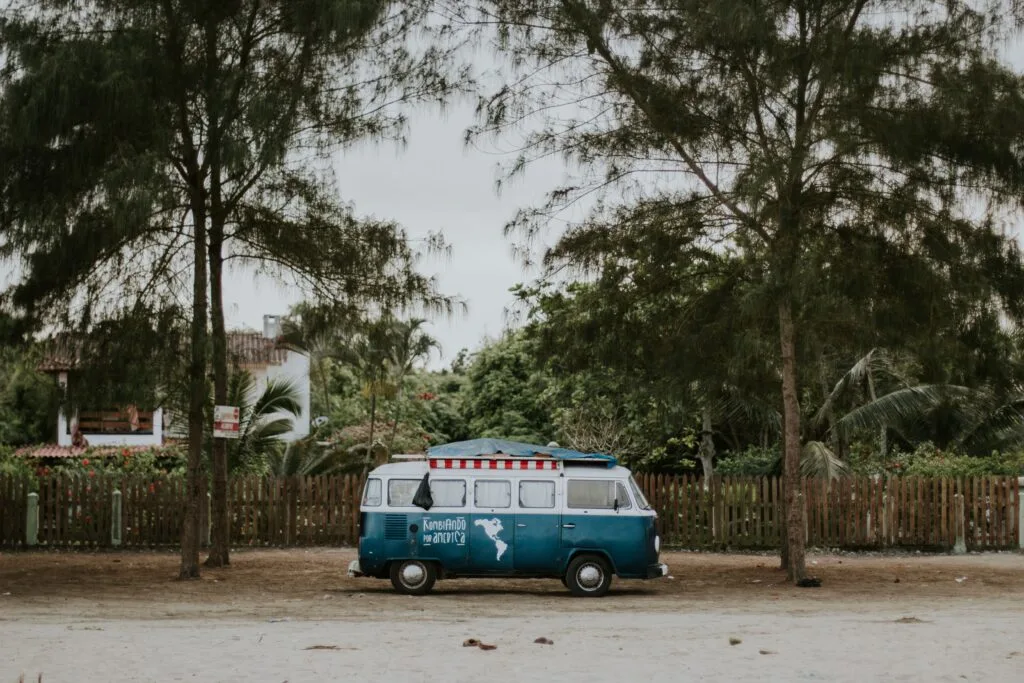 An old VW Campervan sits under some palm trees. It’s painted with a map of South America. The van in in Olón, Ecuador.
