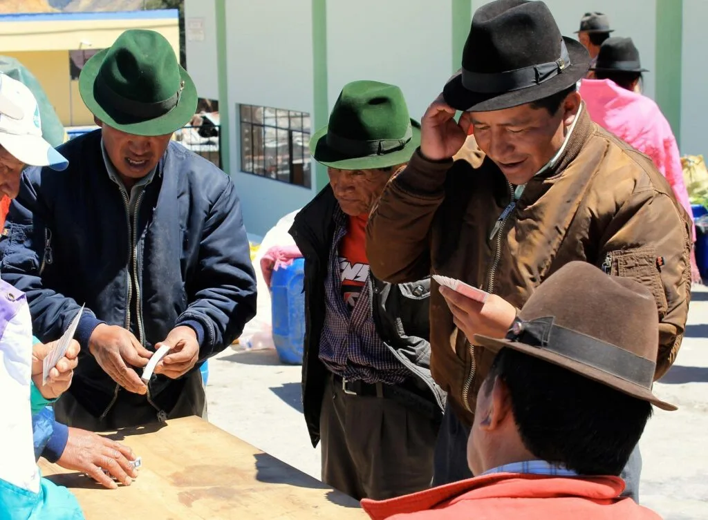 Indigenous Ecuadorian men discuss making a purchase in a market in Zumbahua, Ecuador