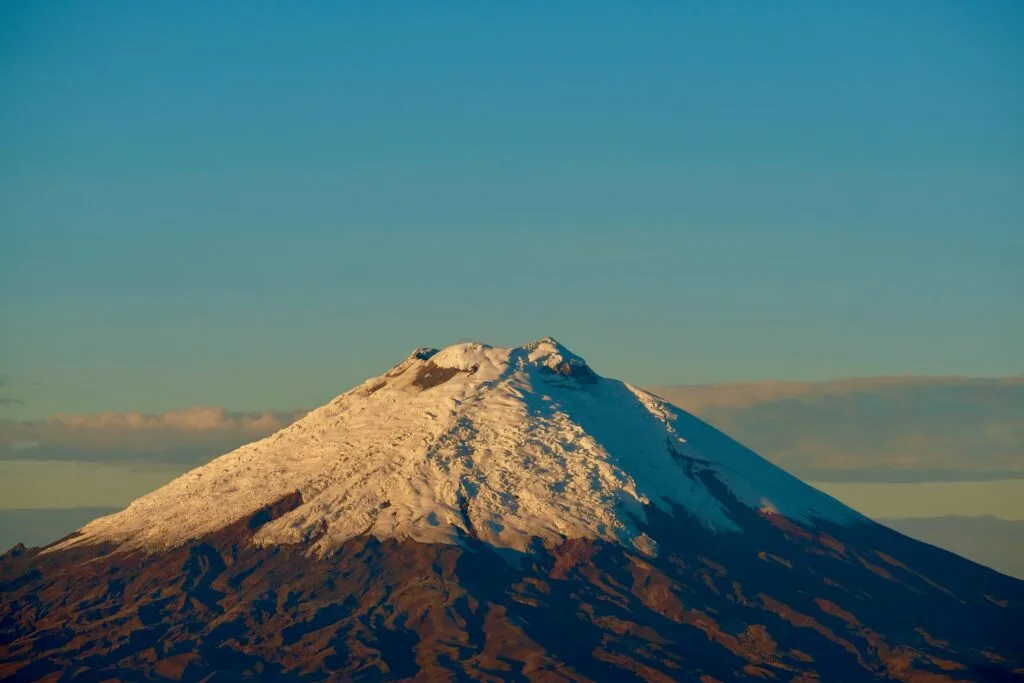 The peak of Cotopaxi volcano is covered in snow on a bright day in Ecuador