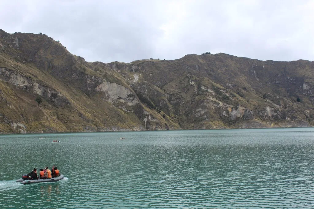 A boat floats in a blue caldera lake at Quilotoa, Ecuador