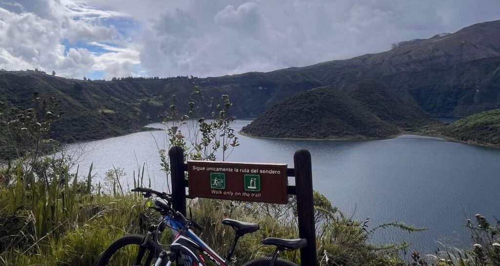 A bike leans against a sign in front of Lak Cuicocha, near Otavalo, Ecuador