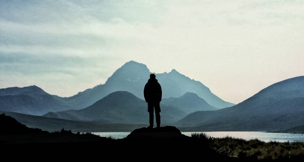 A silhouette of a man looks over a lake towards a volcano in Ecuador