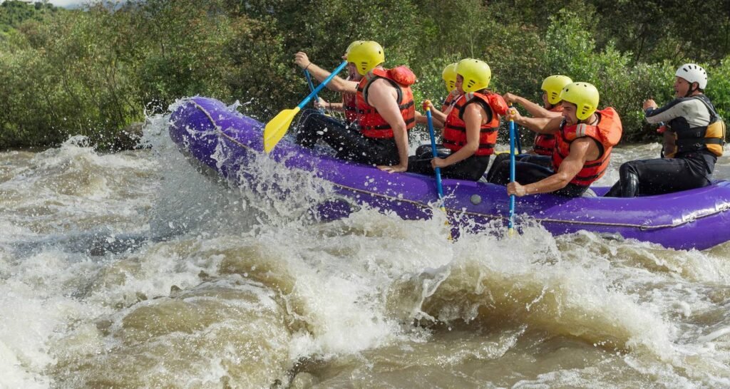 A group of adventurers paddle a raft through white water on a river near Baños, Ecuador