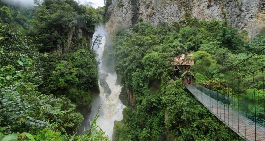 A rope bridge crosses a canyon towards the Pailon del Diablo near Baños, Ecuador