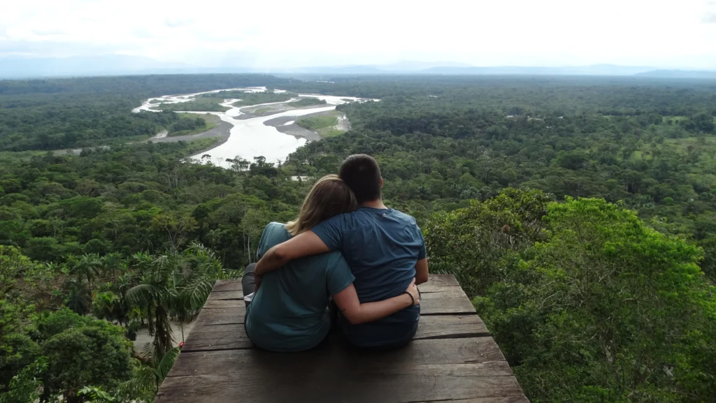 Two people sit on an observation deck high above the canopy of the Amazon in Puyo, Ecuador