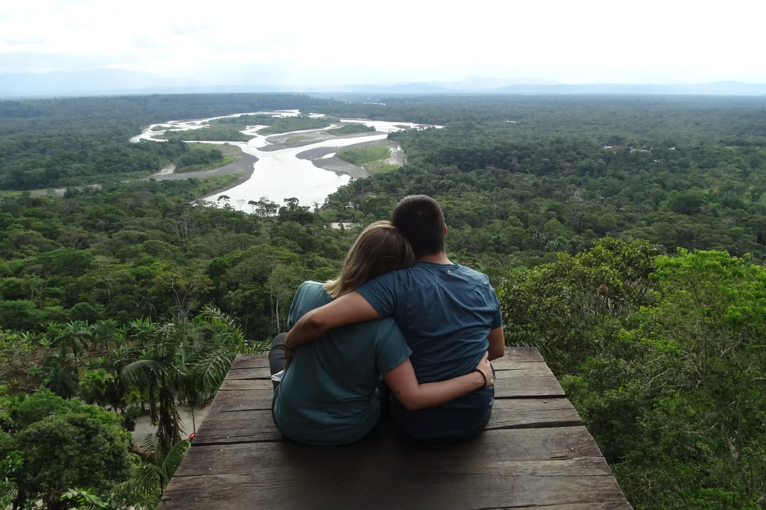 Two people sit on an observation deck high above the canopy of the Amazon in Puyo, Ecuador