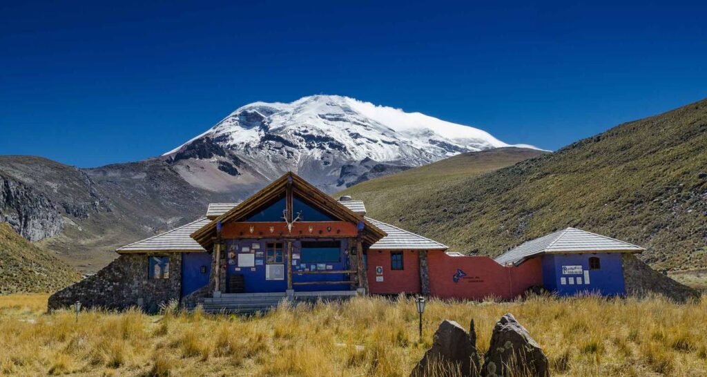 A blue mountain lodge in front of a volcano in Ecuador