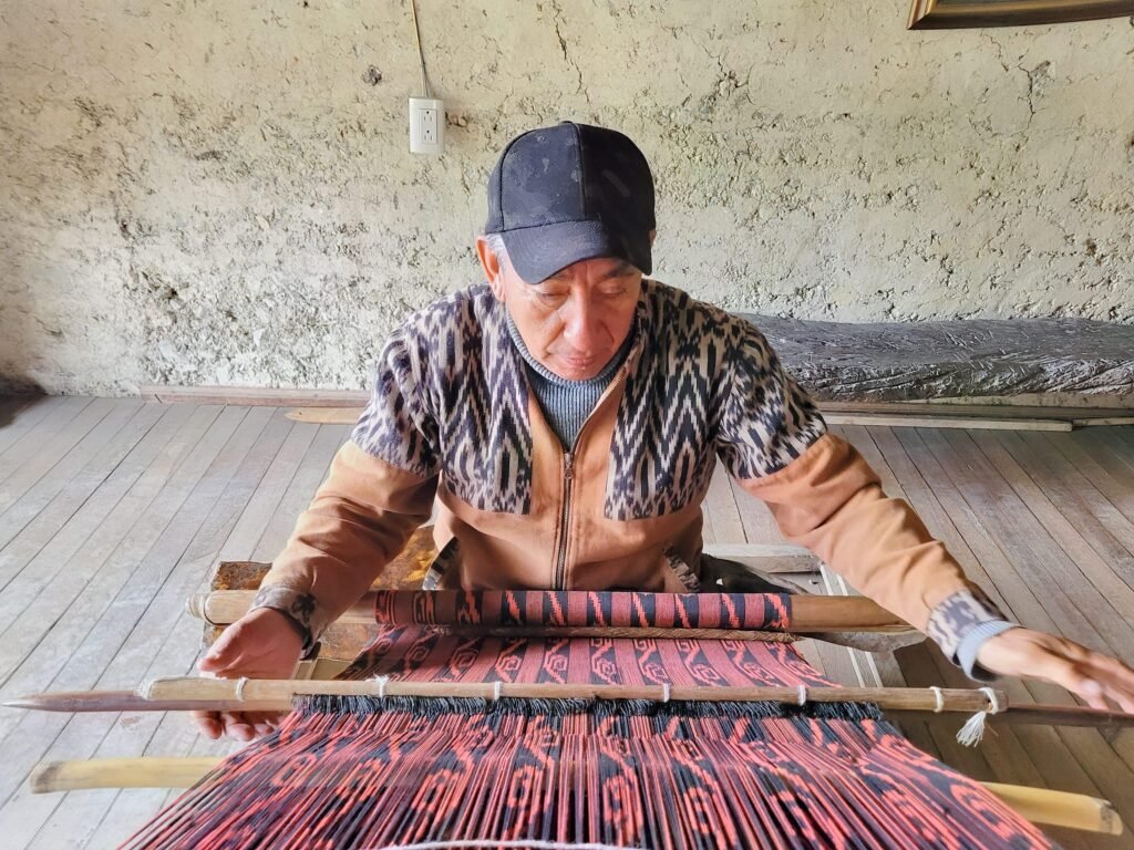 An indigenous man weaves patterned cloth near Cuenca, Ecuador