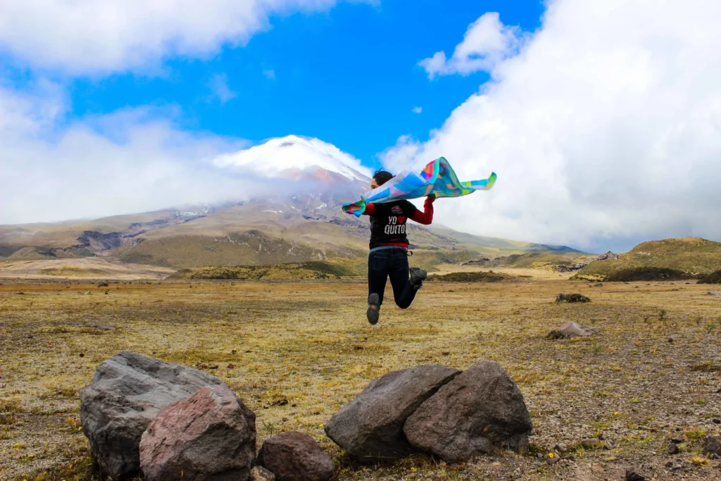 A woman jumps offa rock in front of Cotopaxi, near Quito, Ecuador