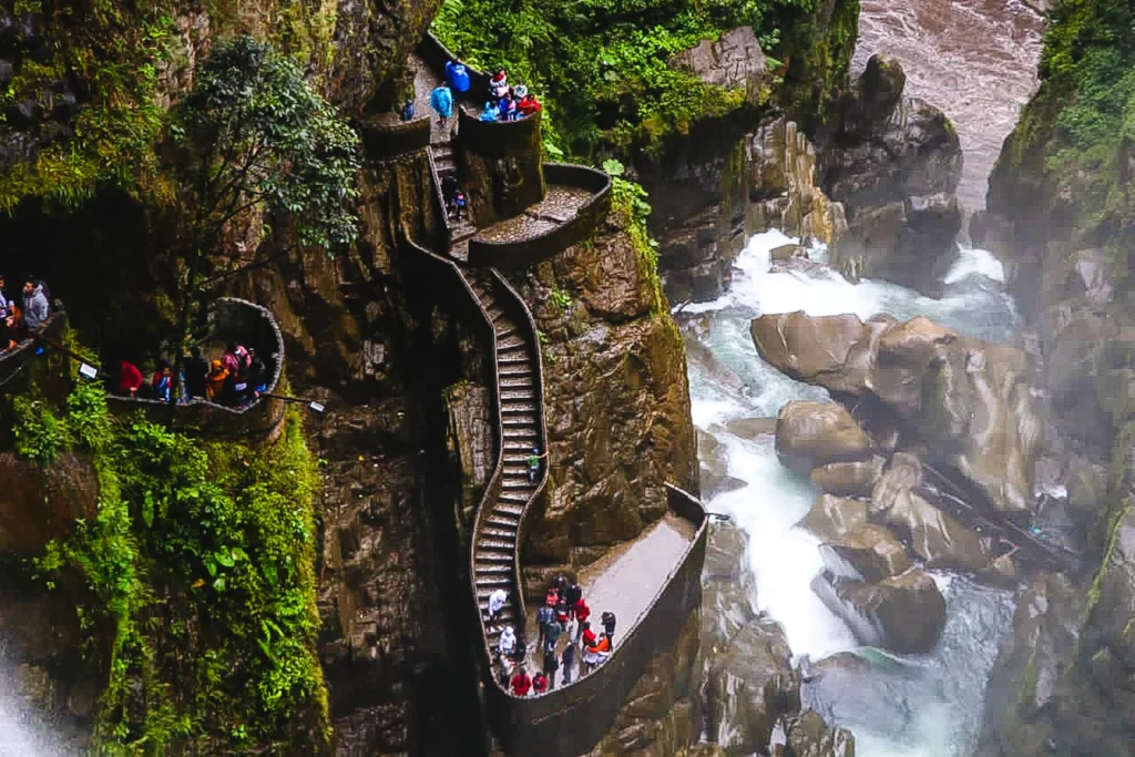 Spray fills the air around tourists climbing the stone steps around the Pailon del Diablo waterfall near Baños, Ecuador