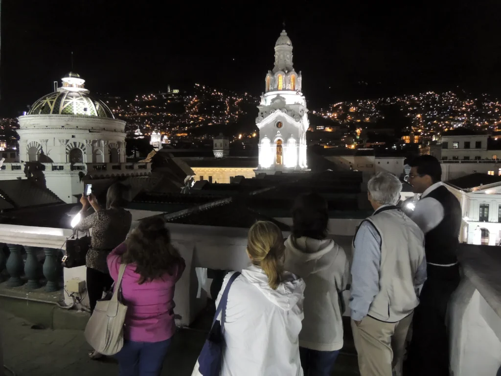 People take photographs of the whitewashed buildings of the historic centre at night in Quito, Ecuador