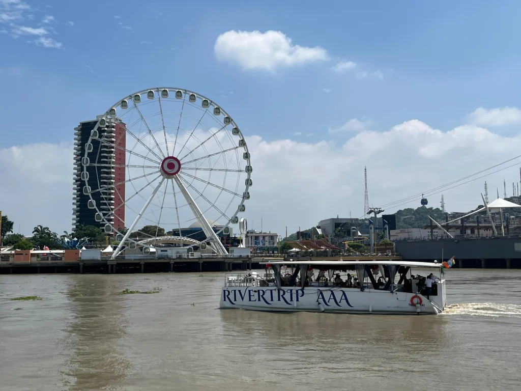 A boat floats past the Pearl of the Pacific ferris wheel by the Guayas River in Guayaquil, Ecuador