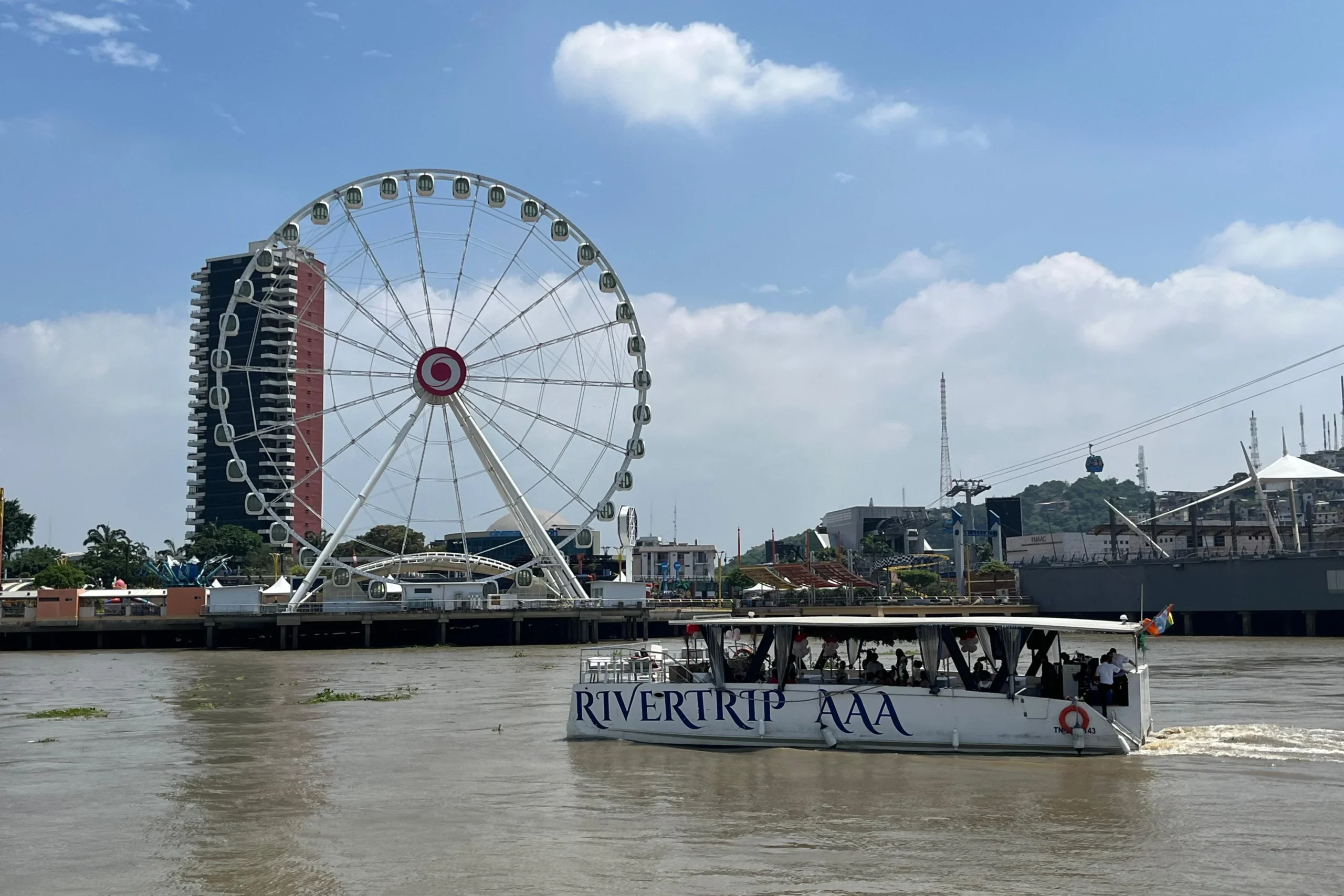A boat floats past the Pearl of the Pacific ferris wheel by the Guayas River in Guayaquil, Ecuador