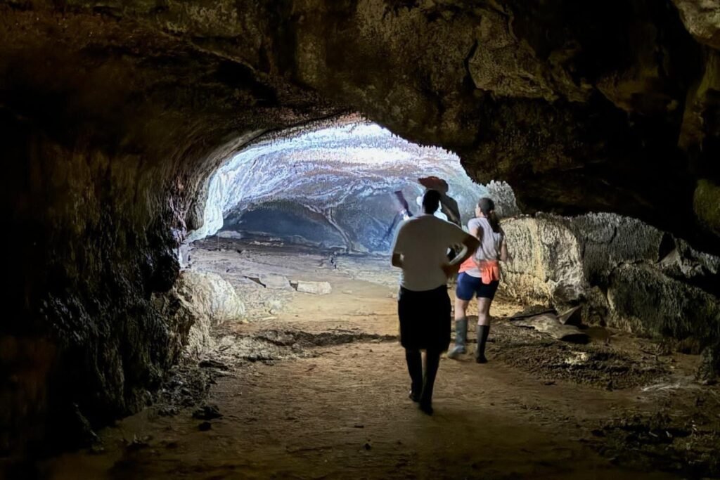 People walk through the dark lava tubes wearing headtorches on Santa Cruz in the Galápagos