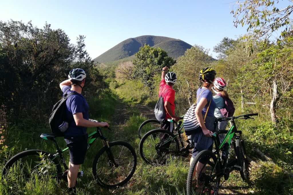 People point at the caldera of a grass covered volcano from the bikes on Floreana Island, Galápagos