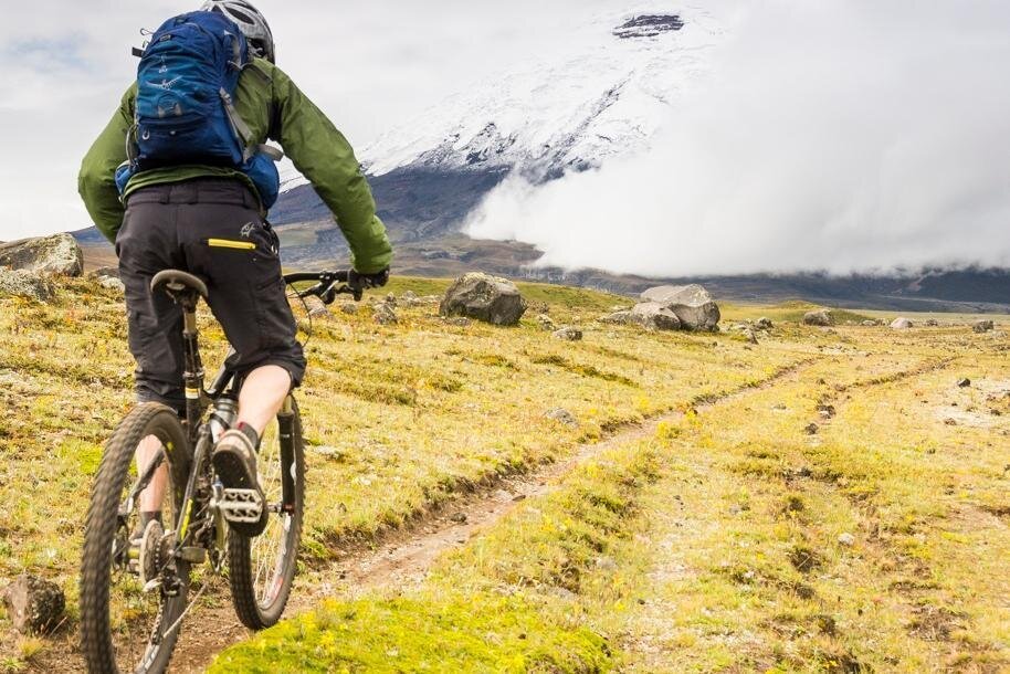 A person rides a mountain bike along a single track towards Cotopaxi, Ecuador