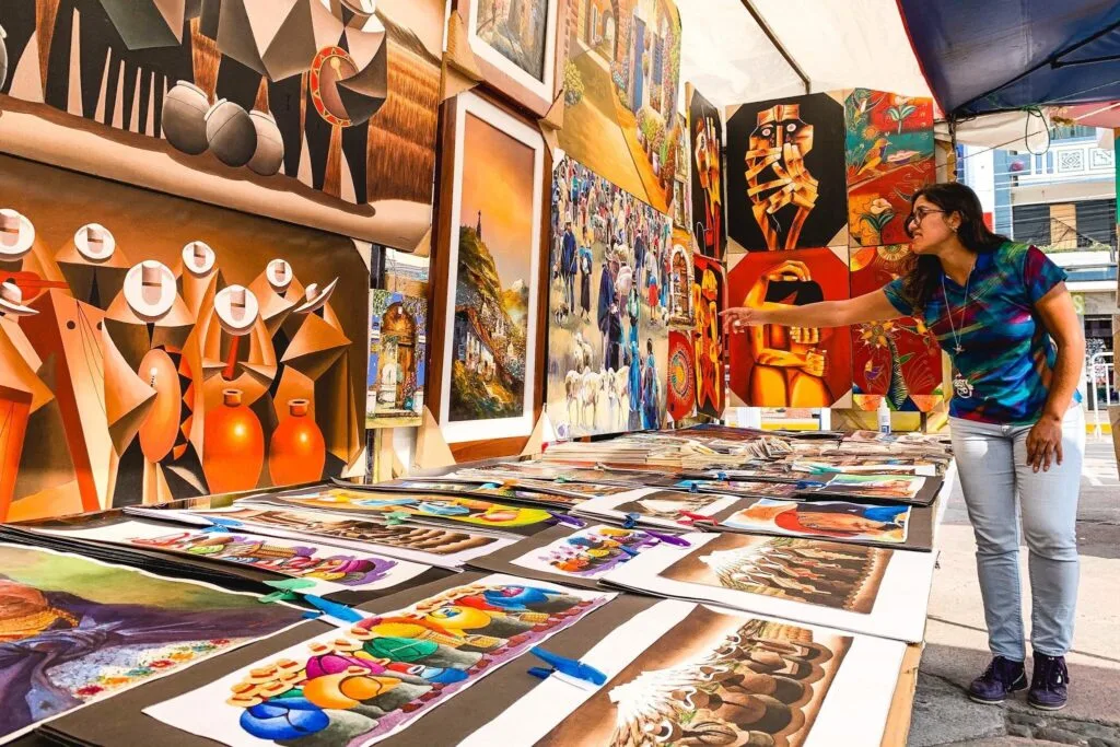 A lady points at paintings in an art shop in Otavalo, Ecuador