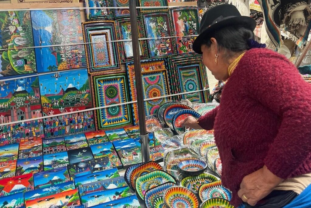 An idigenous woman looks at multicoloured crafts on a market stall in Otavalo, Ecuador