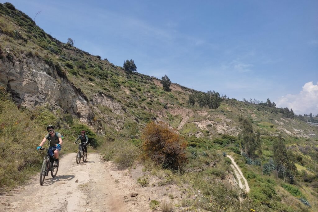 Two people ride mounatin bikes along a trail near Otavalo, Ecuador