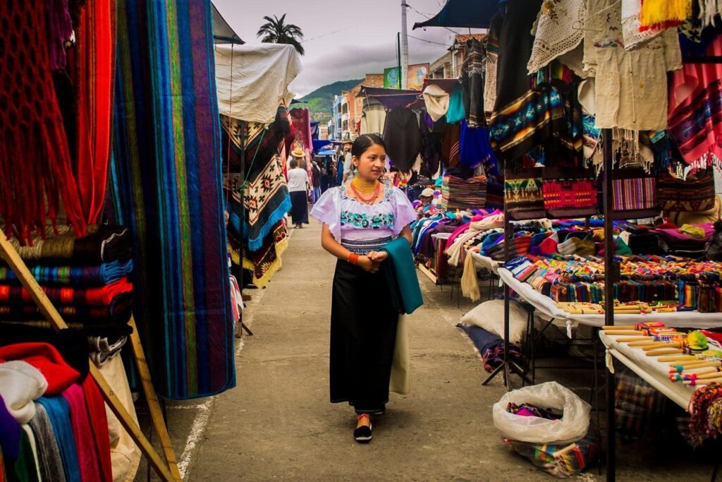 An indigenous woman walks through Plaza de Ponchos looking at the stalls in Otavalo, Ecuador