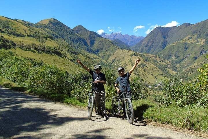 Two people celebrate as they ride through a huge green valley near Mindo, Ecuador