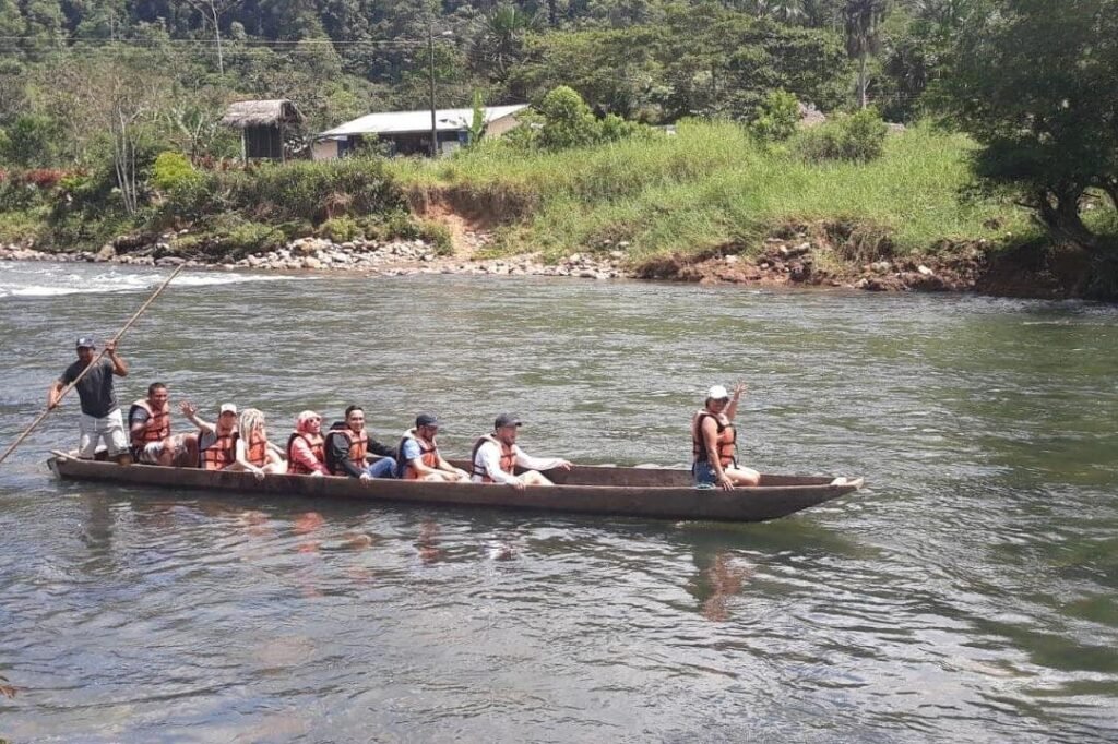 People sail along a river in the Amazon on a long wooden canoe, near Puyo, Ecaudor